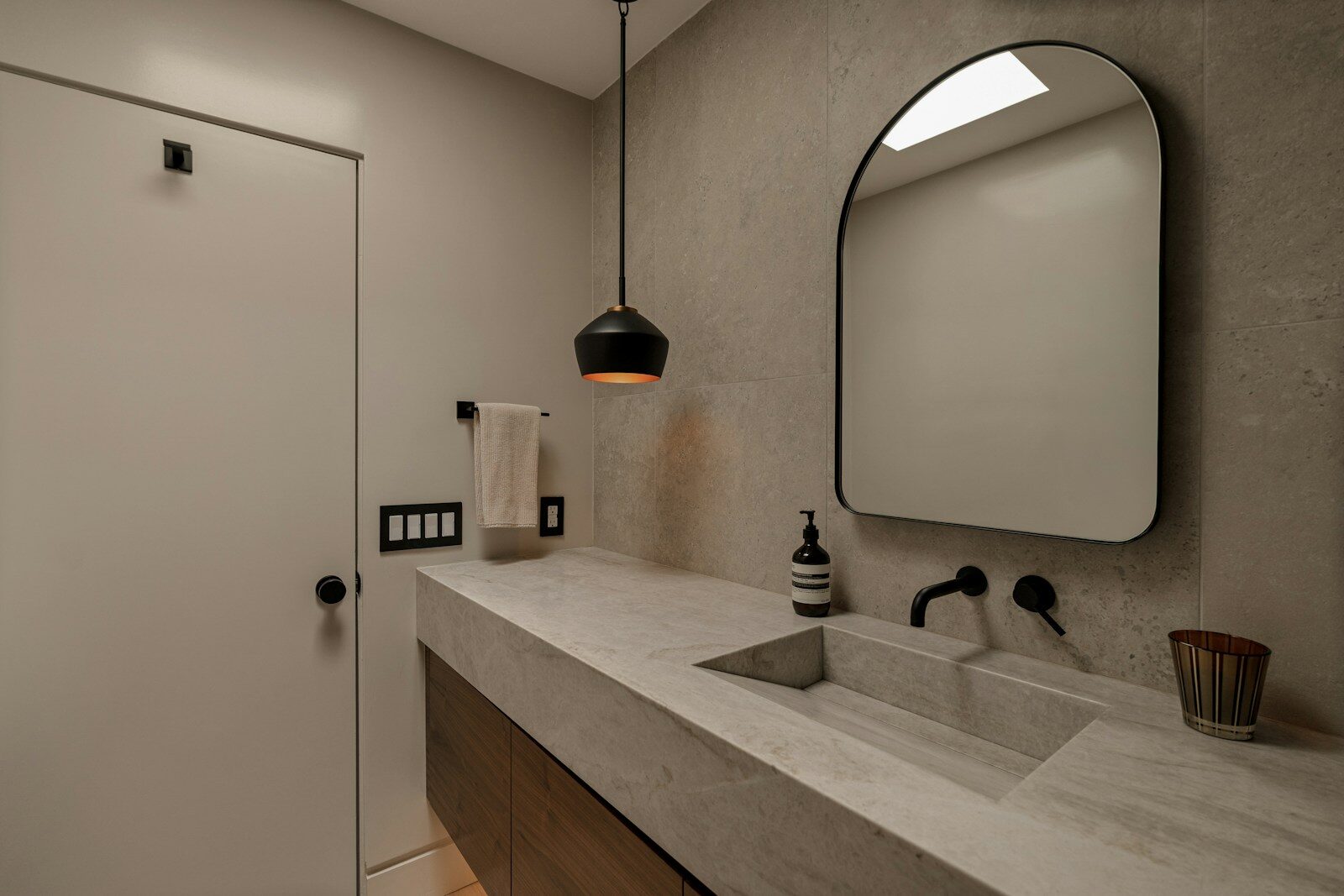 Modern bathroom with concrete sink and black faucet.